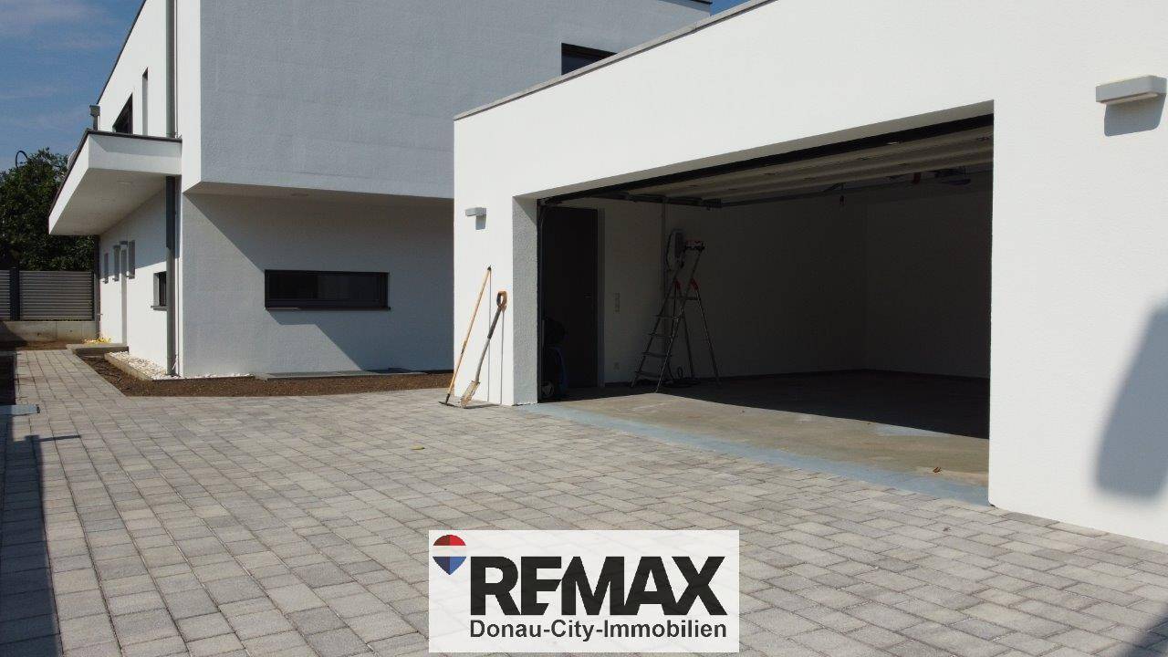 Moderne Doppelgarage mit Zufahrt und sauber gepflastertem Vorplatz, der ausreichend Parkmöglichkeiten bietet.