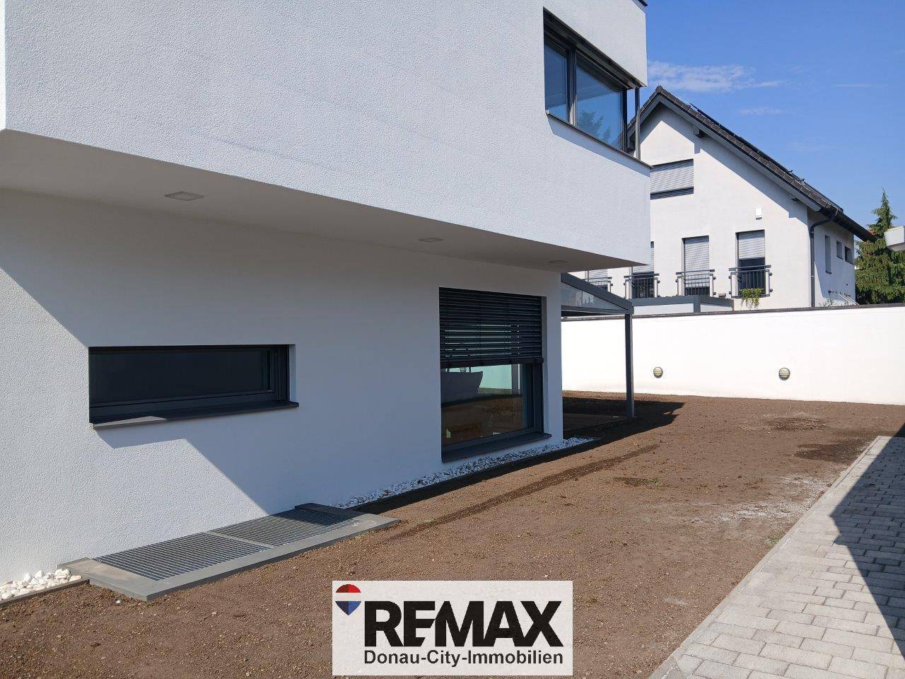 Seitenansicht des Hauses mit einem vorbereiteten Gartenbereich und einem Fenster mit Rollladen.