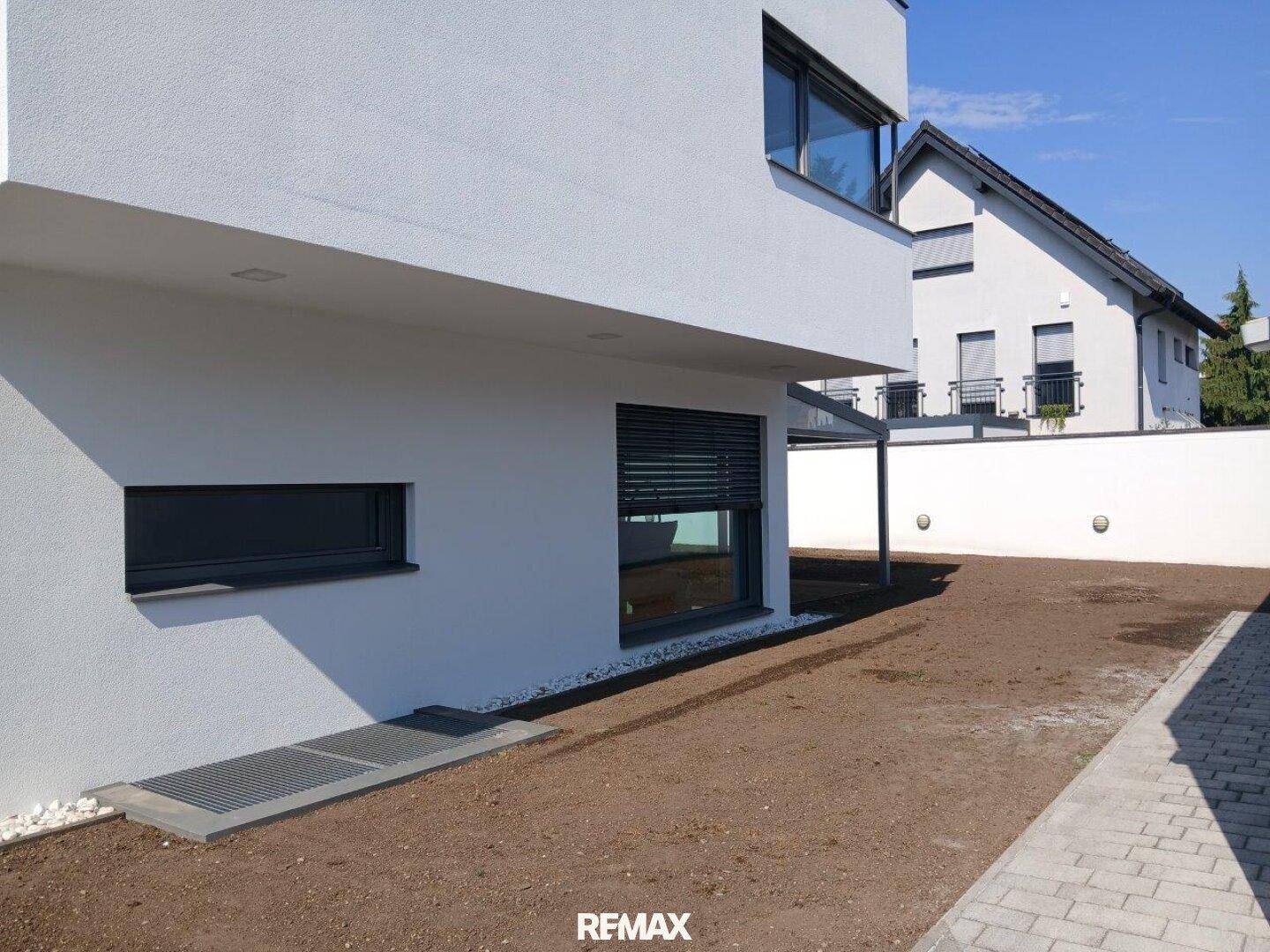 Neu angelegter Gartenbereich neben dem Haus mit Fenster und Rollladen.