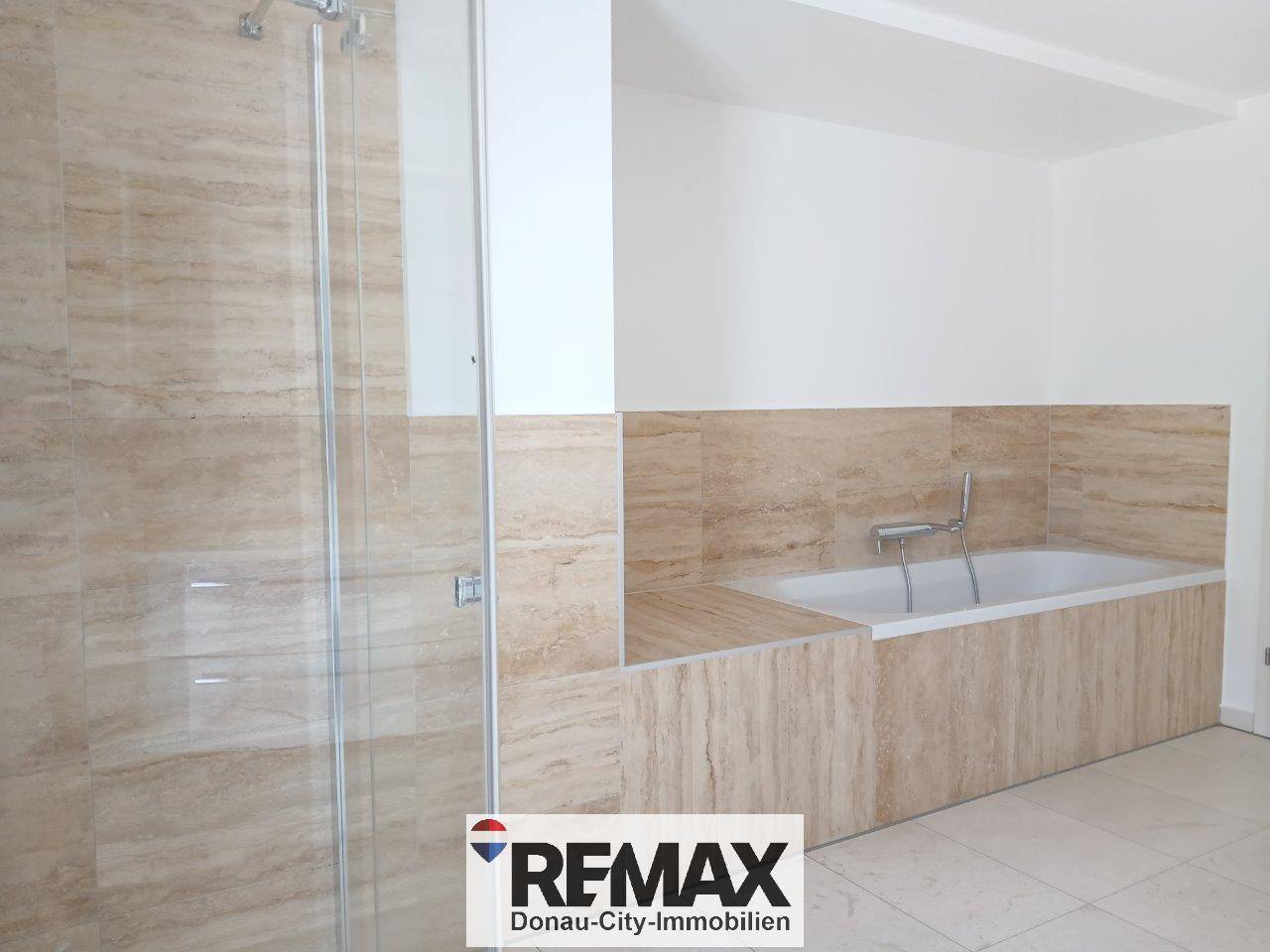 Geräumiges Badezimmer mit begehbarer Dusche und integrierter Badewanne, alles in hellen Fliesen.