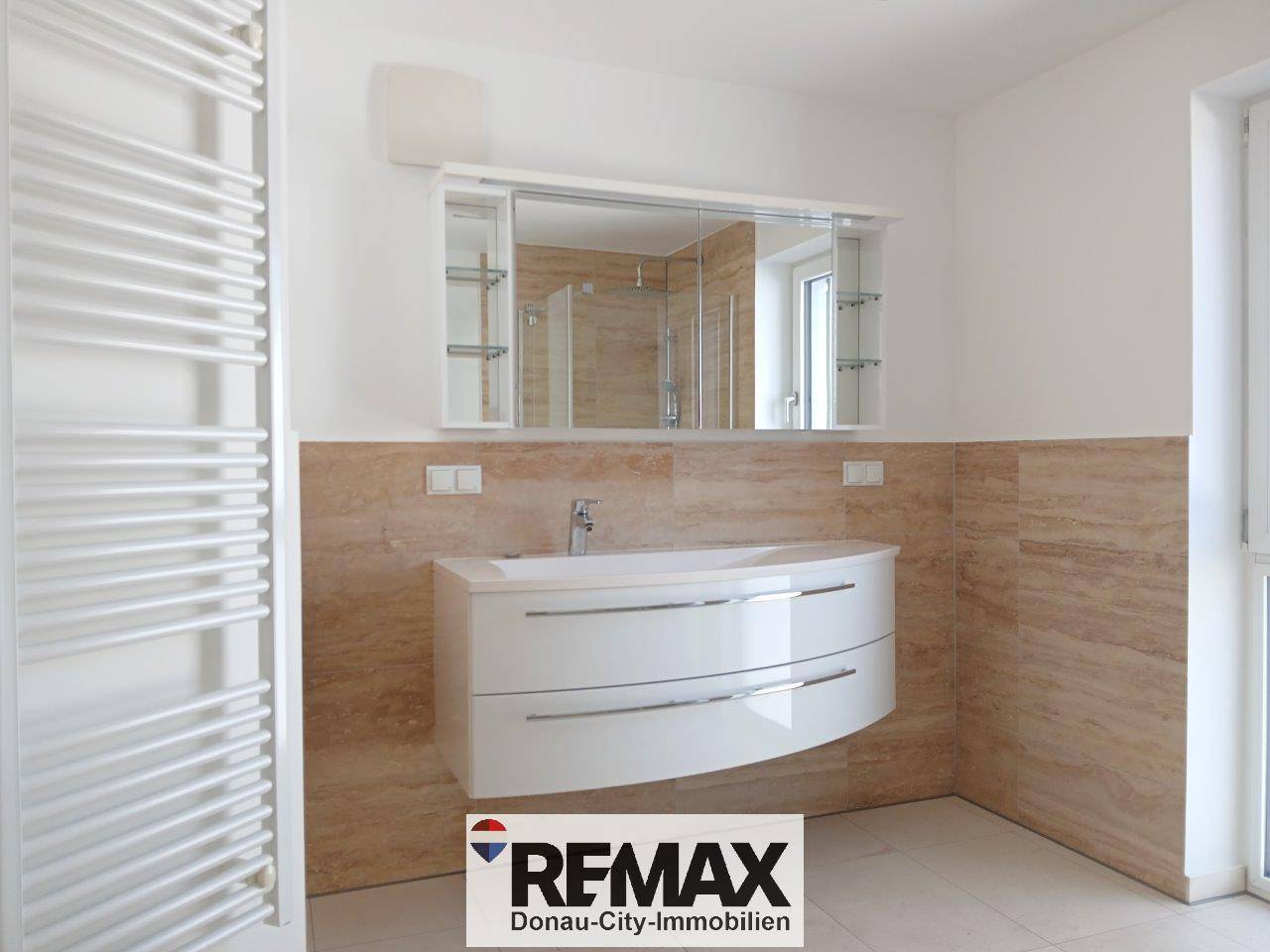 Modernes Badezimmer mit elegantem Waschbecken, Spiegelschrank und beheiztem Handtuchhalter.