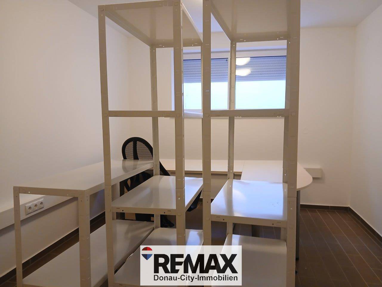 Helles Büro mit Regalsystem und Fenster, das viel Tageslicht hereinlässt und eine angenehme Arbeitsatmosphäre schafft.