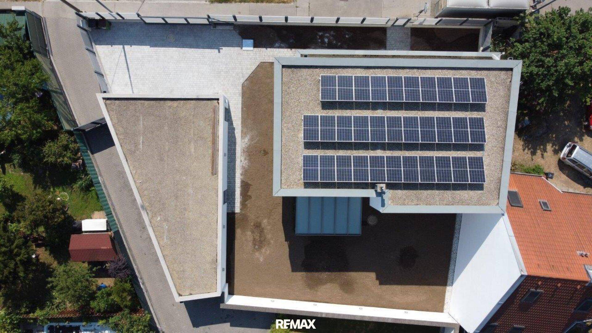 Luftaufnahme des modernen Hauses mit Photovoltaikanlage auf dem Flachdach.