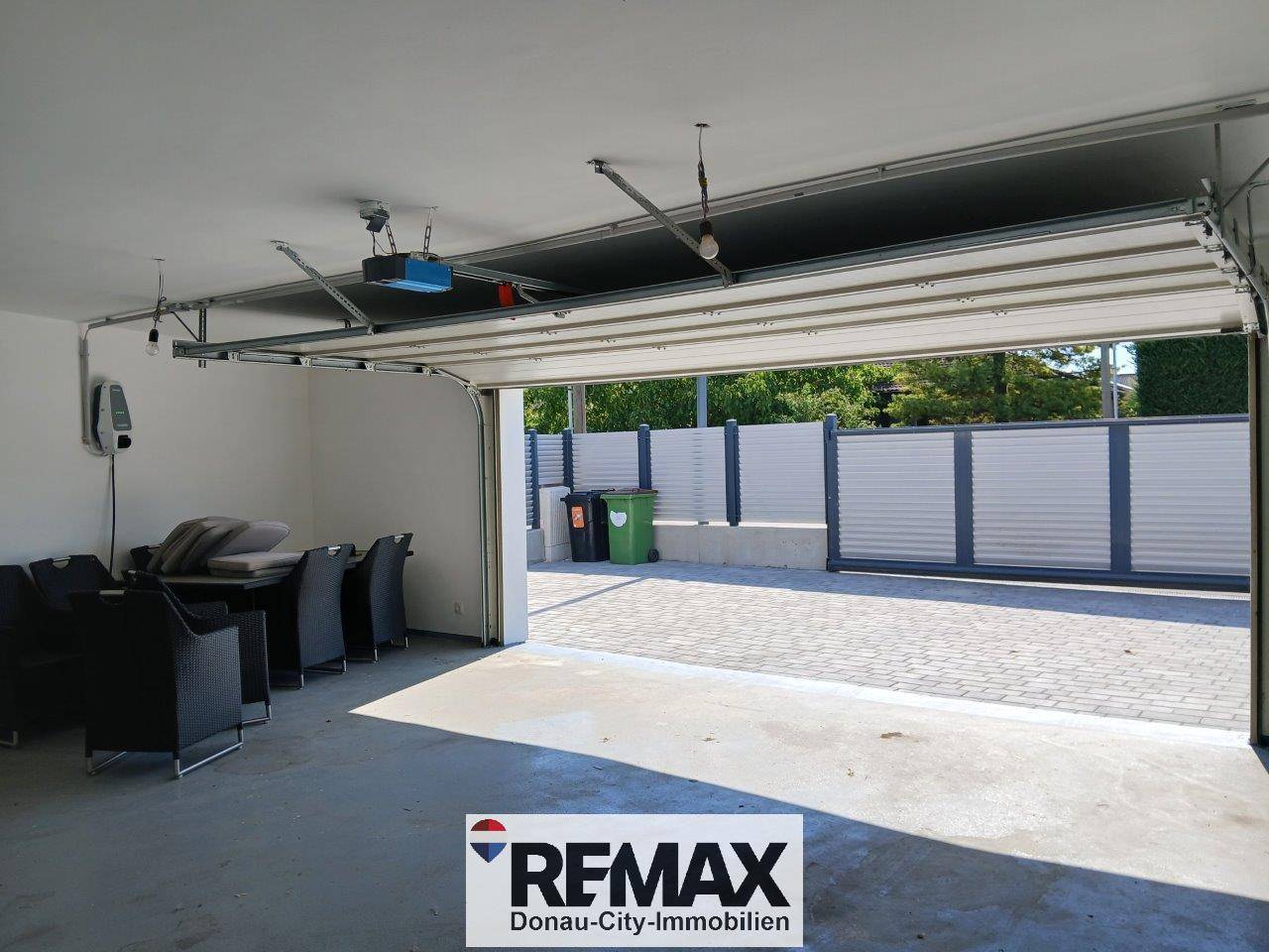 Geräumige Garage mit offenem Tor, die auch als Abstellraum genutzt wird und einen Blick nach draußen bietet.