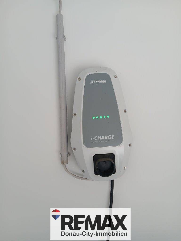 Nahaufnahme einer modernen Ladestation für Elektrofahrzeuge an einer weißen Wand installiert.