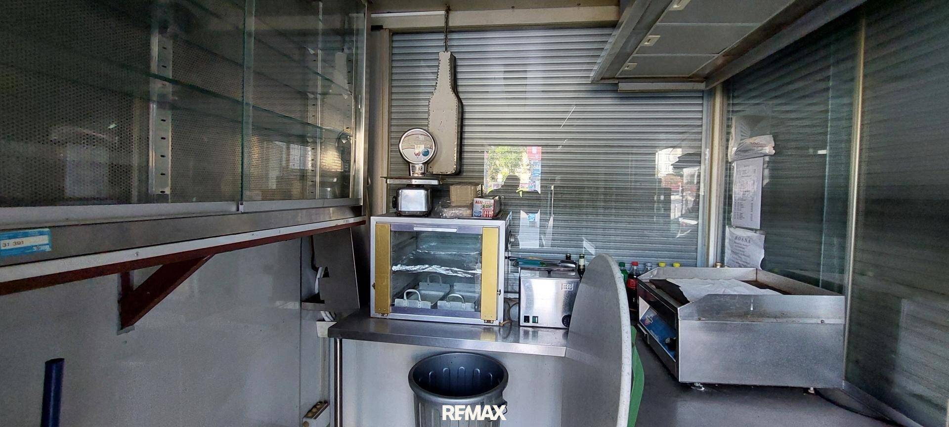 Innenansicht des Kiosks mit Edelstahloberflächen, Regalen und geschlossenen Rollläden.