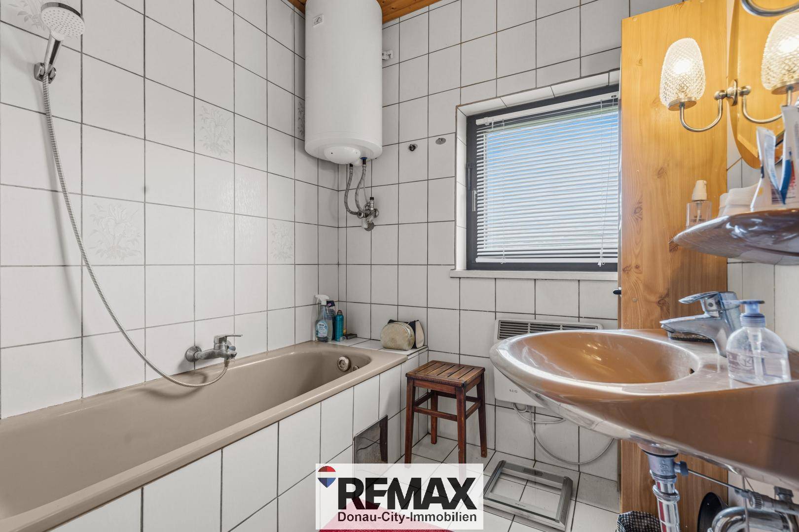 Badezimmer mit Badewanne, Waschbecken und Fenster, gefliest in hellem Design.