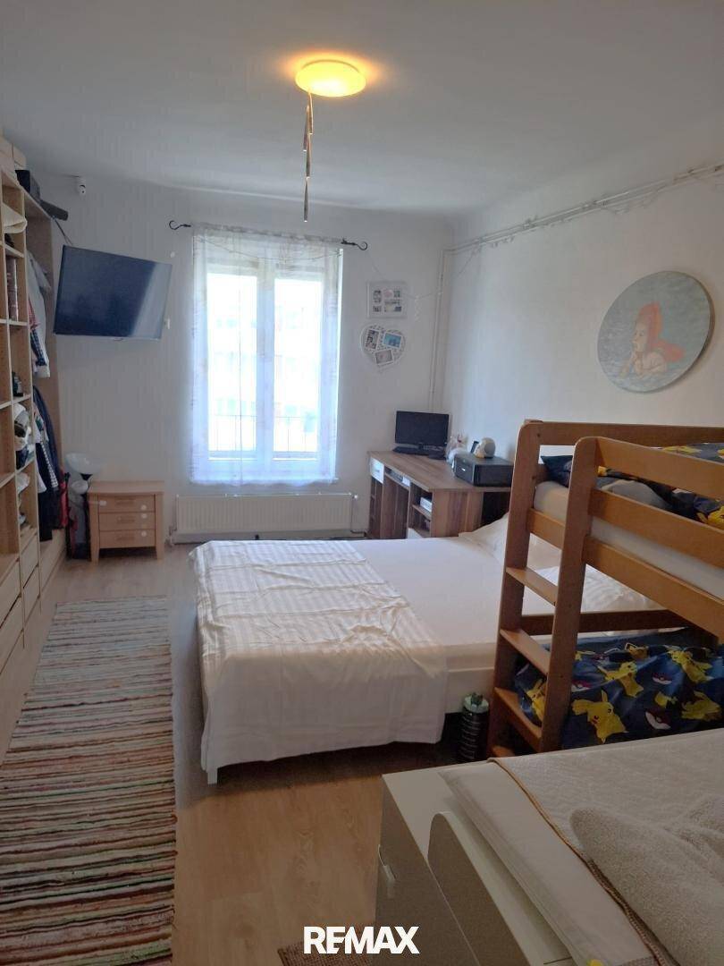 Helles Schlafzimmer mit Etagenbett, Einzelbett und großem Einbauschrank für Kleidung.