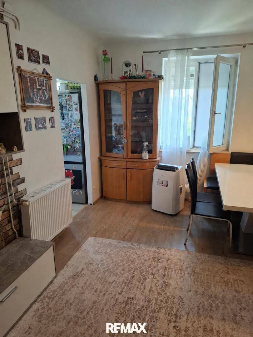 Heller Wohn-Essbereich mit Holzboden, großem Fenster und traditionellem Holzschrank.