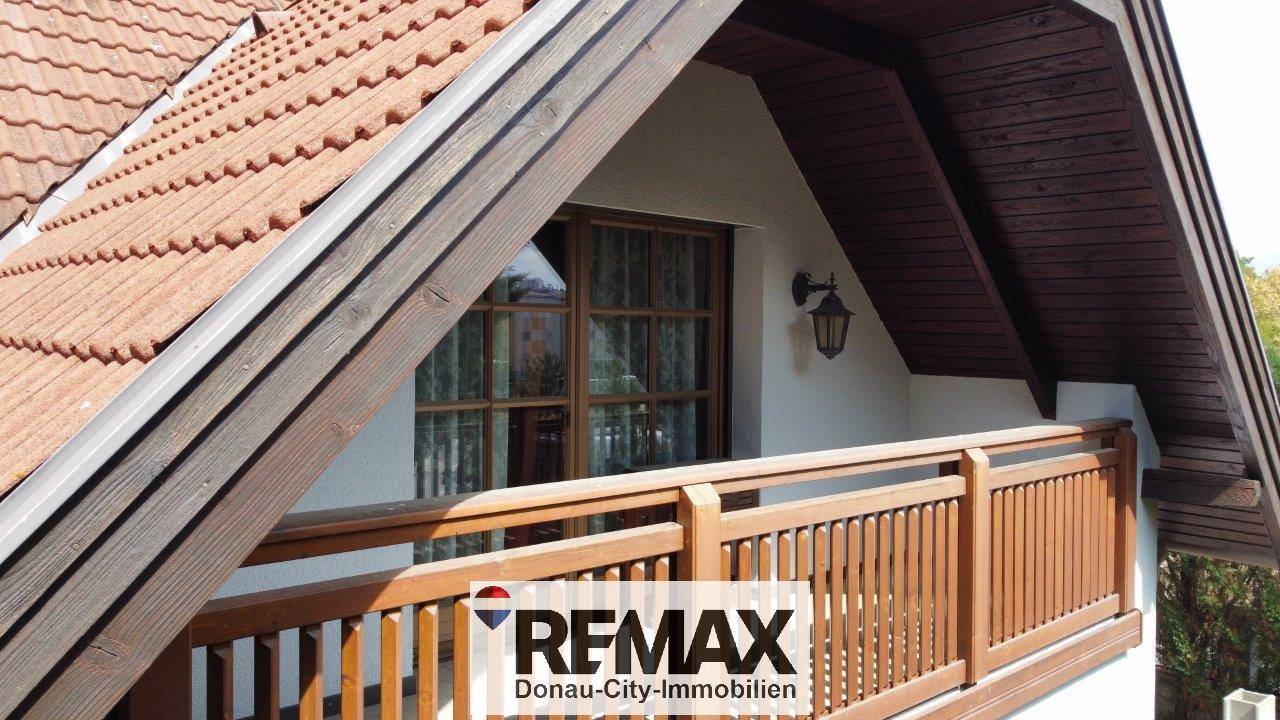 Holzbalkon mit traditionellem Geländer und schützendem Dachüberstand, ideal zum Entspannen.