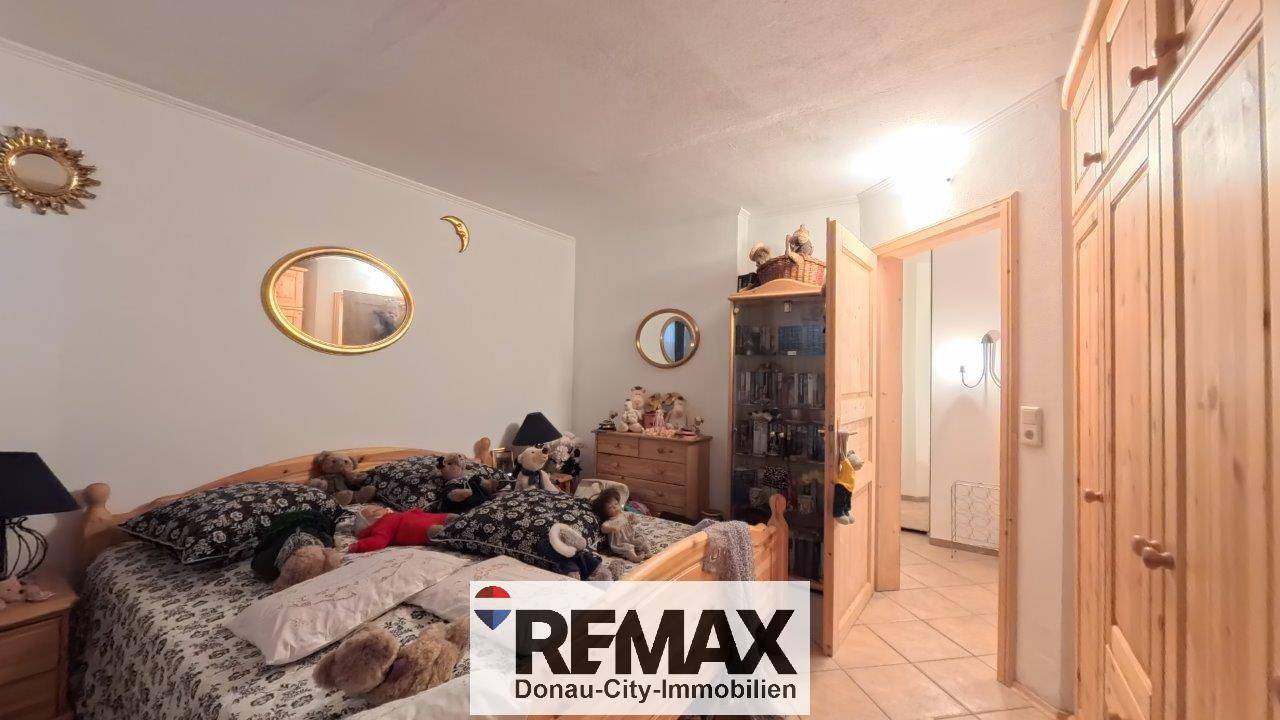 Schlafzimmer im Untergeschoss mit Doppelbett, Holzschrank und Fliesenboden, der pflegeleicht ist.