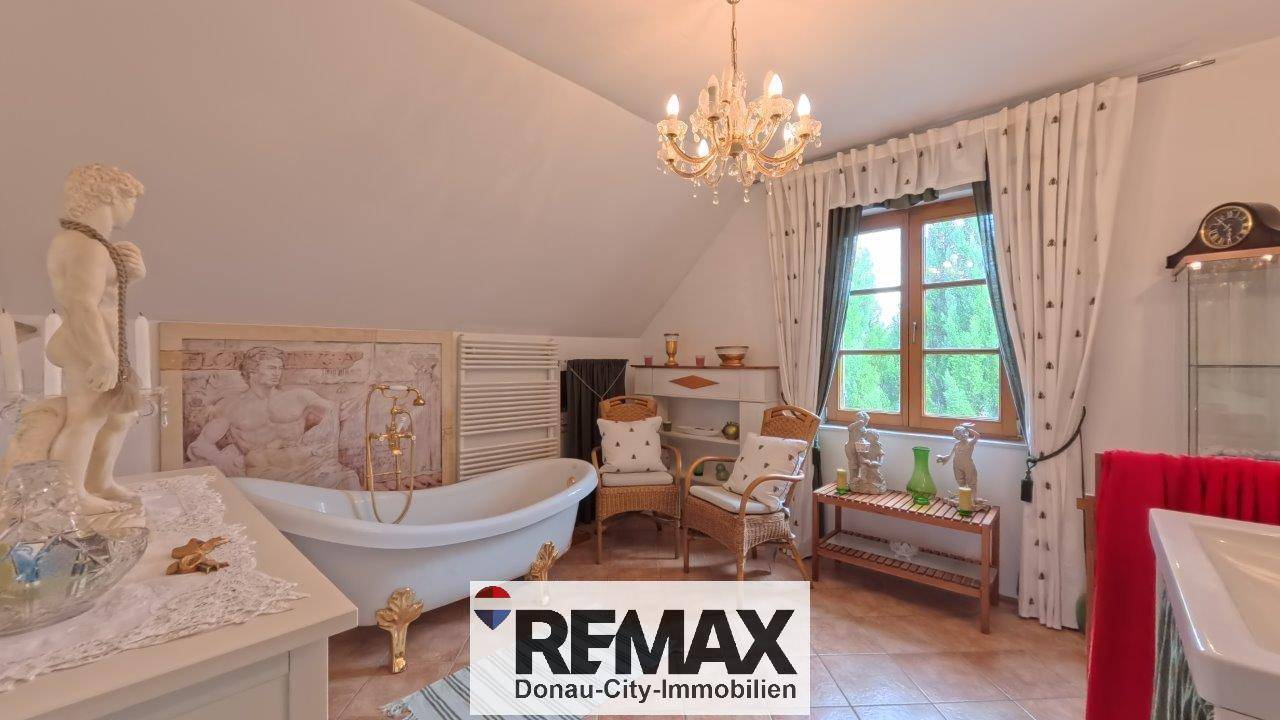 Geräumiges Badezimmer im Dachgeschoss mit freistehender Badewanne und Fenster, das viel Licht spendet.