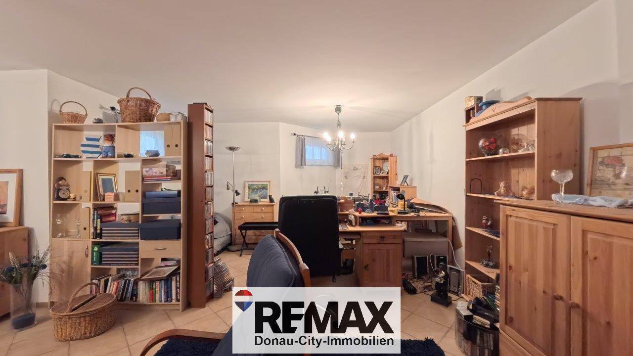 Arbeitsbereich im Untergeschoss mit Schreibtisch, Regalen und gemütlicher Einrichtung, ideal für Home-Office.