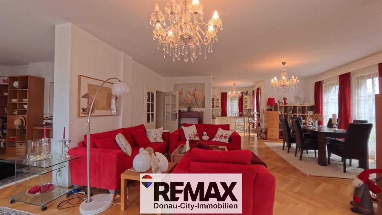 Offener Wohn- und Essbereich mit roten Sofas und eleganten Kronleuchtern, die den Raum stilvoll beleuchten.