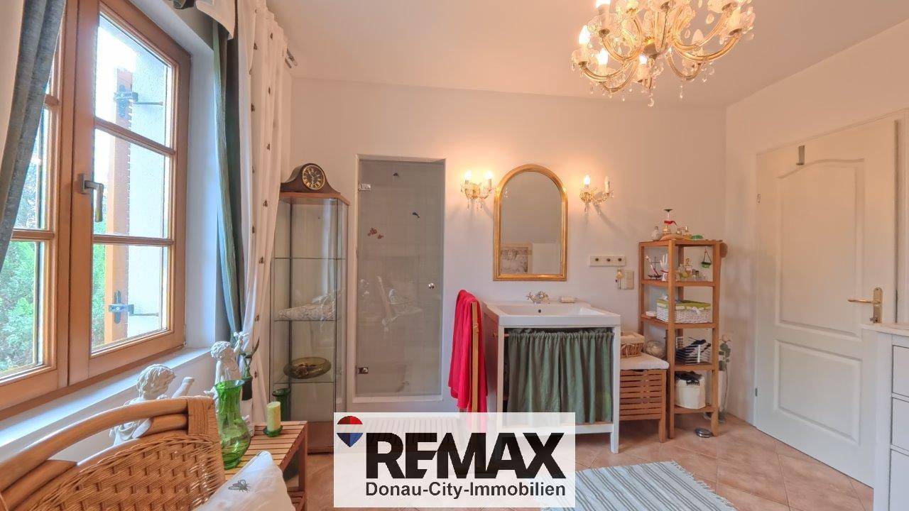 Helles Badezimmer mit Duschkabine, Einzelwaschbecken und Fenster, das eine angenehme Atmosphäre schafft.