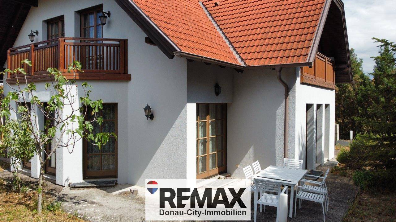 Terrasse an der Rückseite des Hauses mit Esstisch und Stühlen für Mahlzeiten im Freien.