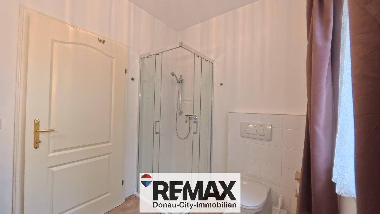 Helles Badezimmer mit Duschkabine und Wand-WC, das eine moderne und platzsparende Lösung darstellt.