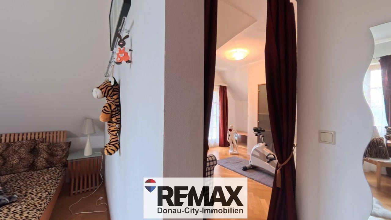 Flur mit Blick in ein weiteres Zimmer im Dachgeschoss, das eine offene Raumgestaltung andeutet.