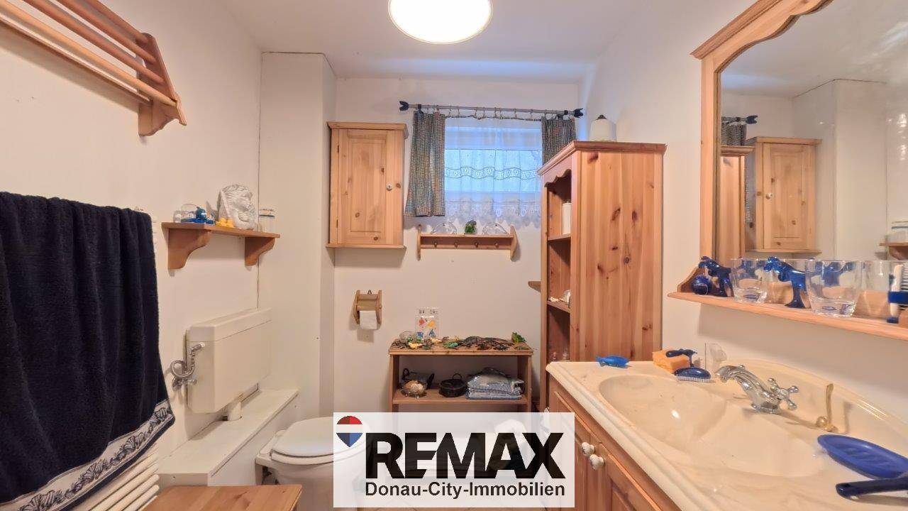 Badezimmer im Untergeschoss mit Holzmöbeln, WC und Waschbecken, das funktional eingerichtet ist.