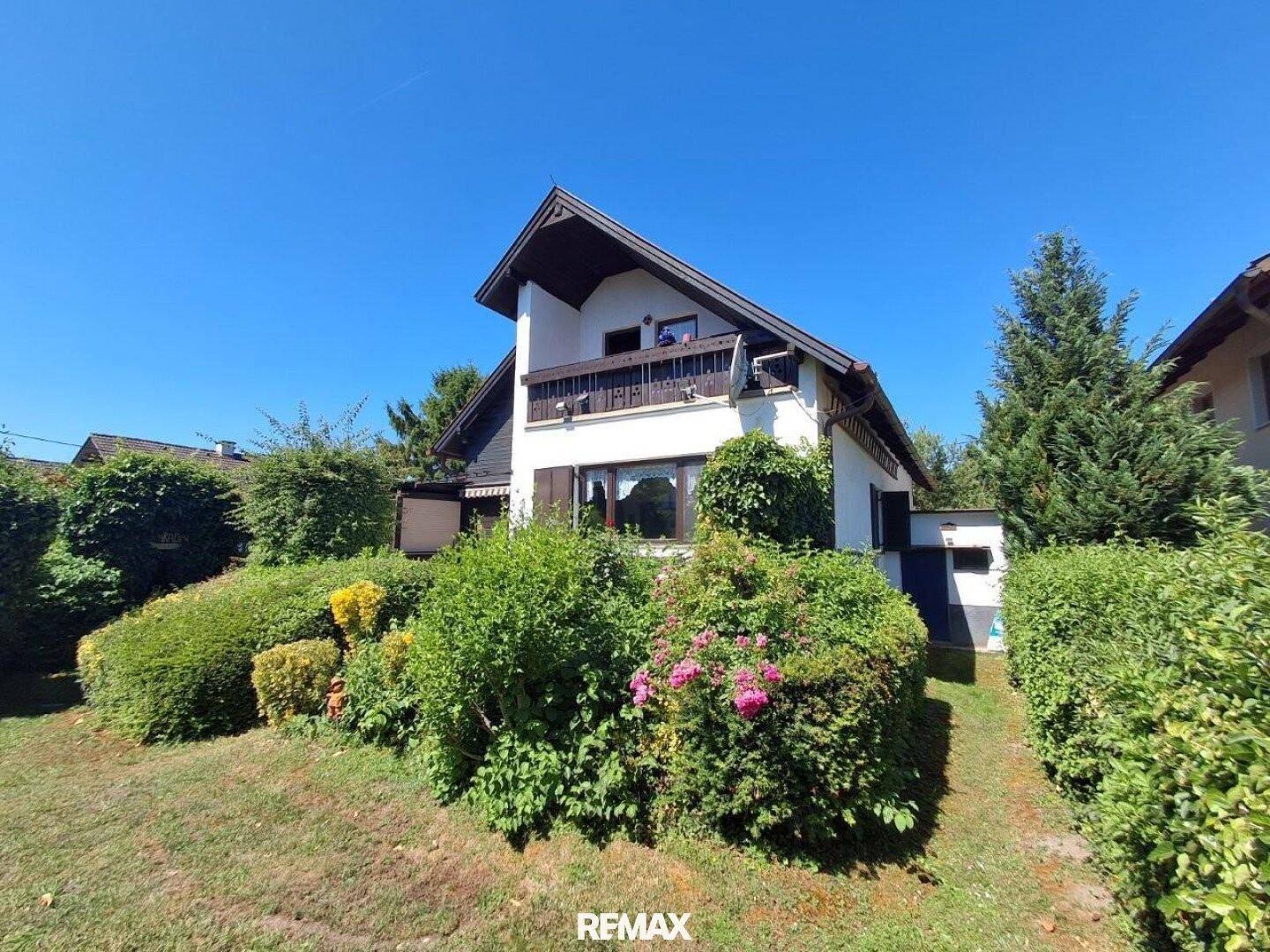 Freistehendes Haus mit Satteldach, umgeben von einem großen, gepflegten Garten.