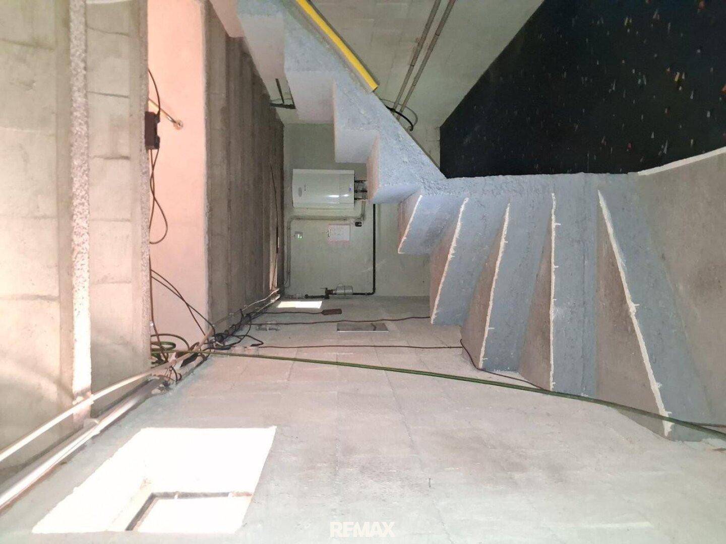Unfertiger Kellerraum mit Betonboden und sichtbaren Installationen, bereit für den weiteren Ausbau.