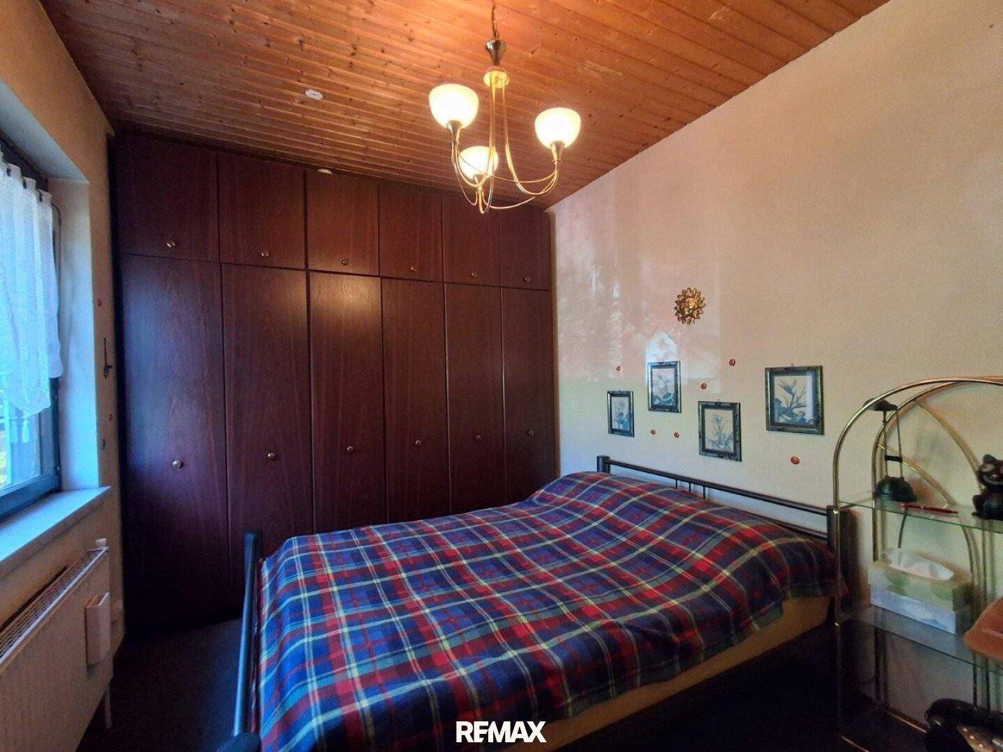 Schlafzimmer mit Doppelbett, großen Einbauschränken und Holzdecke, gemütlich und funktional eingerichtet.