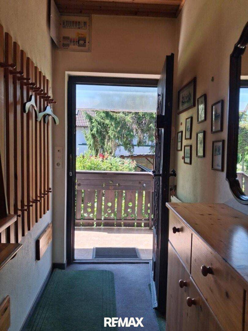 Eingangsbereich mit Garderobe, Kommode und Blick auf den Balkon, der viel Licht hereinlässt.