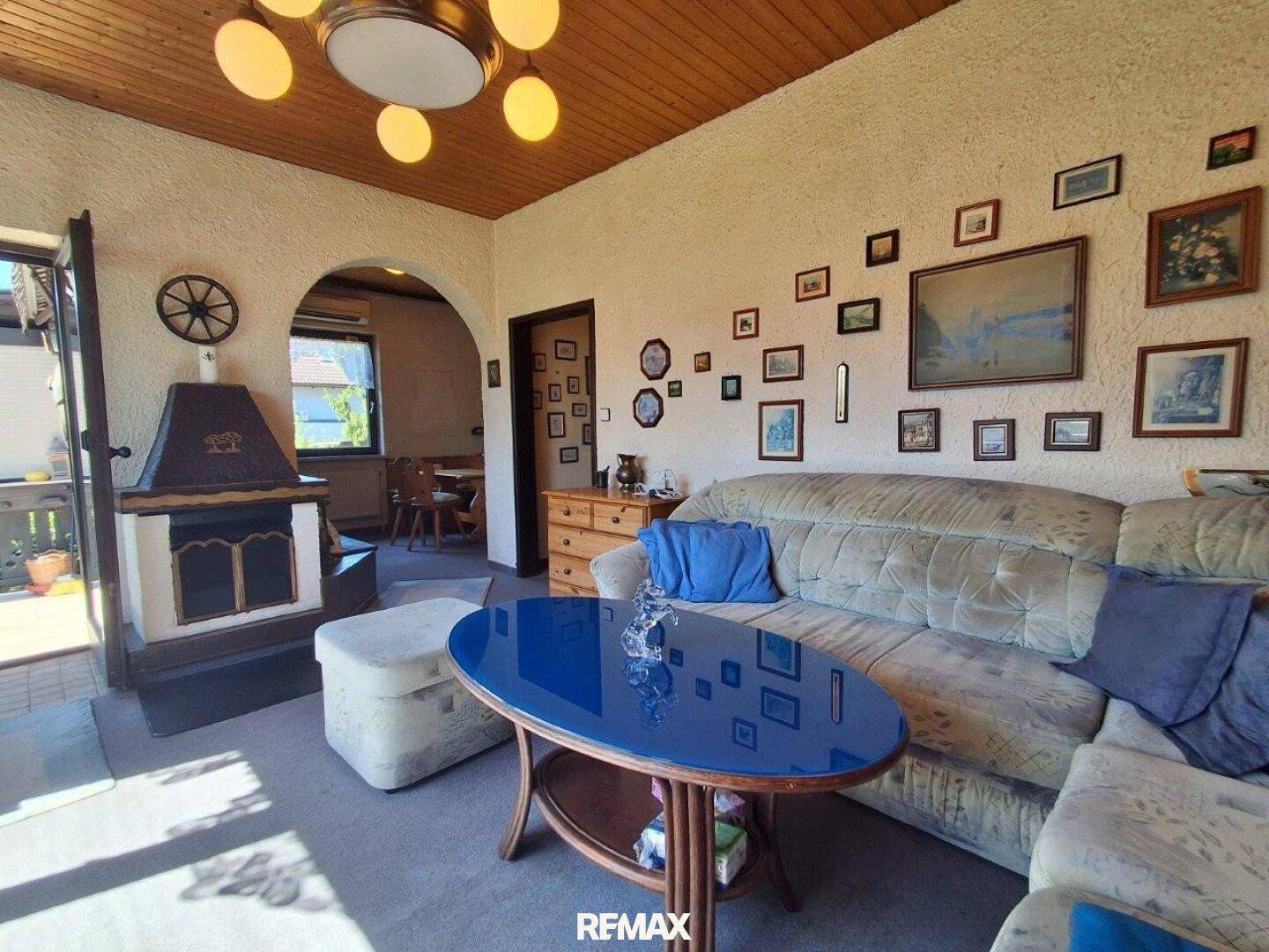 Gemütliches Wohnzimmer mit Sofa, Couchtisch und Kaminofen, dekoriert mit vielen Bildern an der Wand.