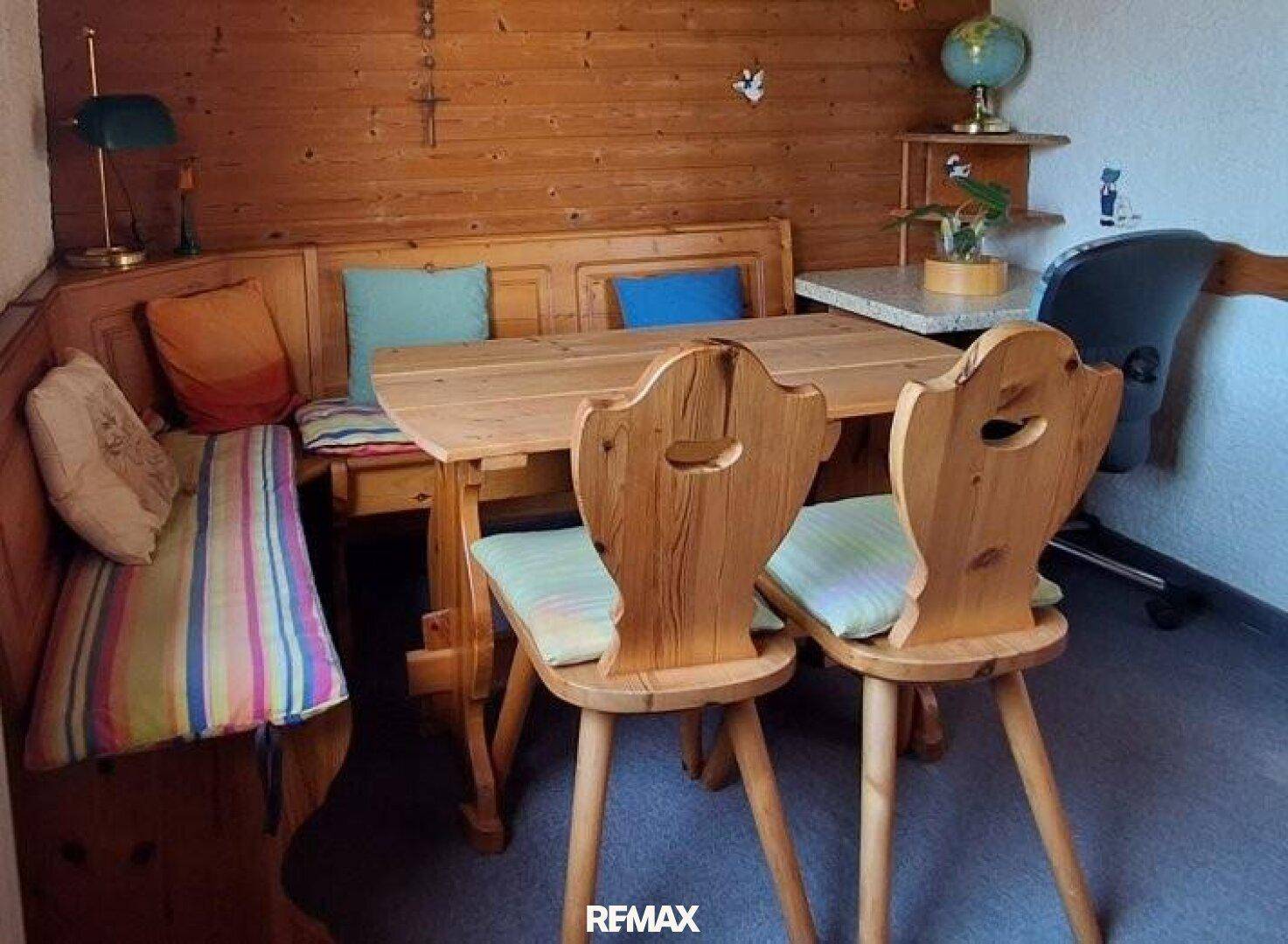 Rustikaler Essbereich mit Holztäfelung, Eckbank und traditionellen Holzstühlen, ideal für gemütliche Mahlzeiten.