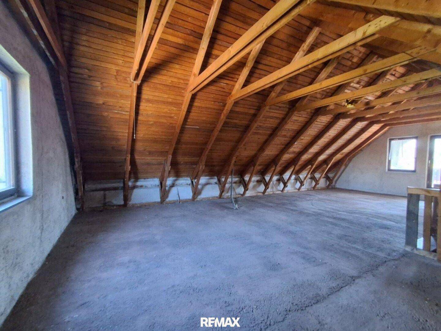 Geräumiger, unausgebauter Dachboden mit sichtbaren Holzbalken und Dachschrägen, bereit für den Ausbau.