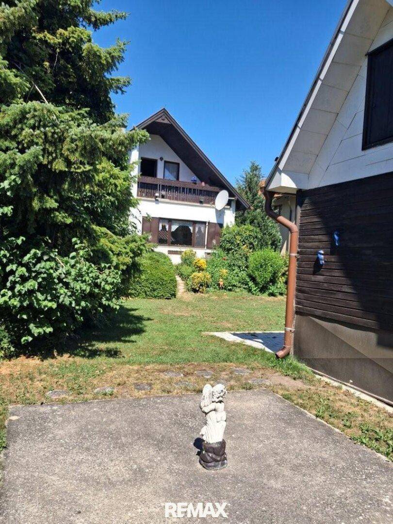 Vorderansicht des Hauses mit gepflegtem Garten, Rasenfläche und einer kleinen Terrasse.