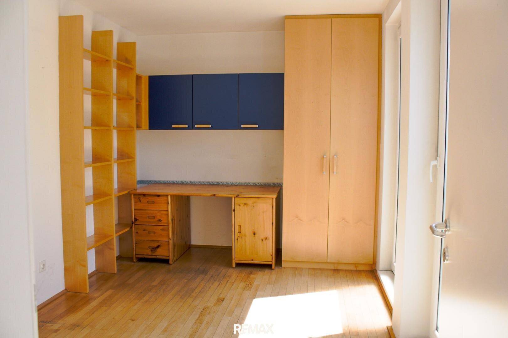 Helles Arbeitszimmer mit Holzmöbeln, Regalen und Schrank, ideal für Home-Office oder Kinderzimmer.