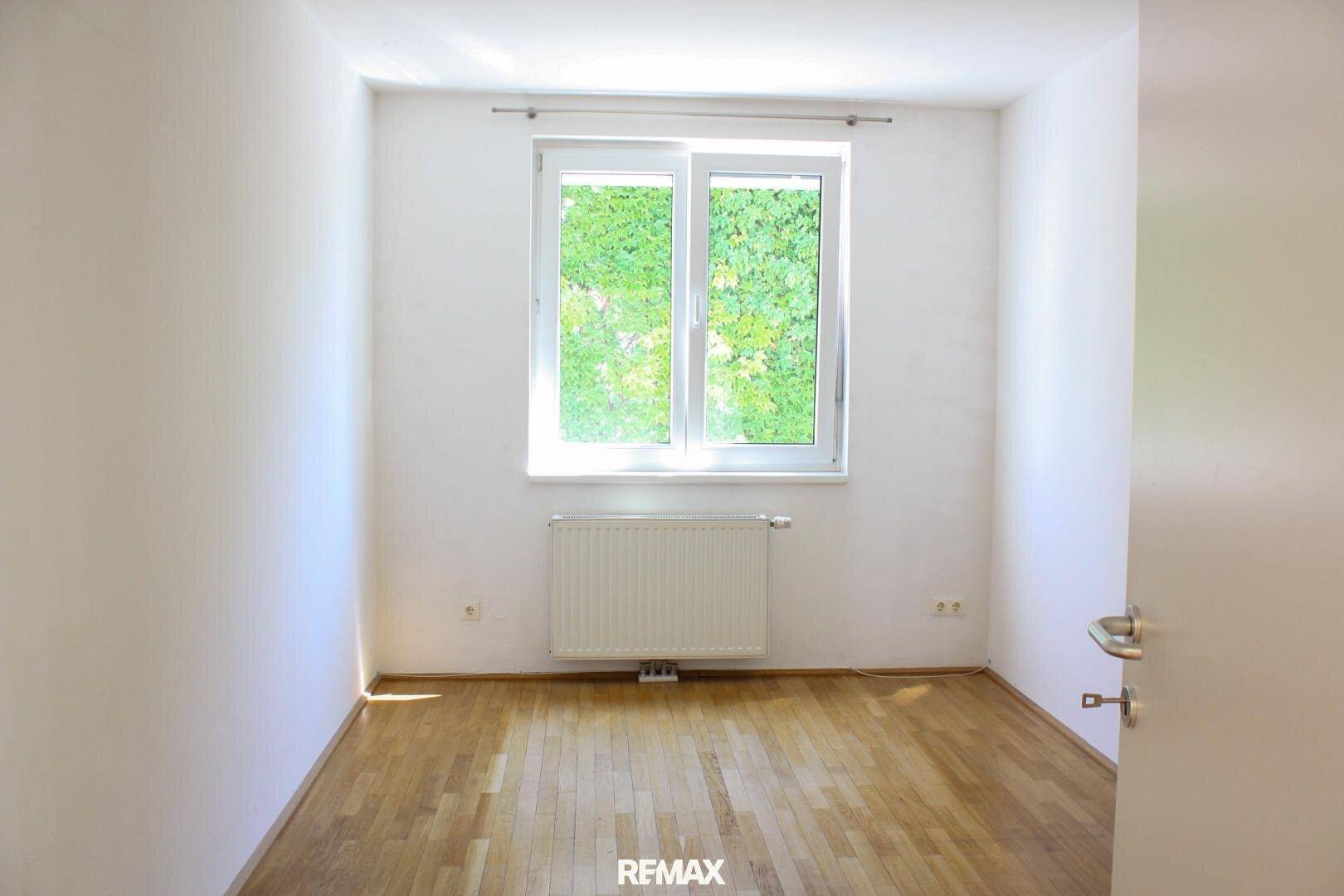 Gemütliches Schlafzimmer mit Parkettboden und Fenster, das viel natürliches Licht hereinlässt.