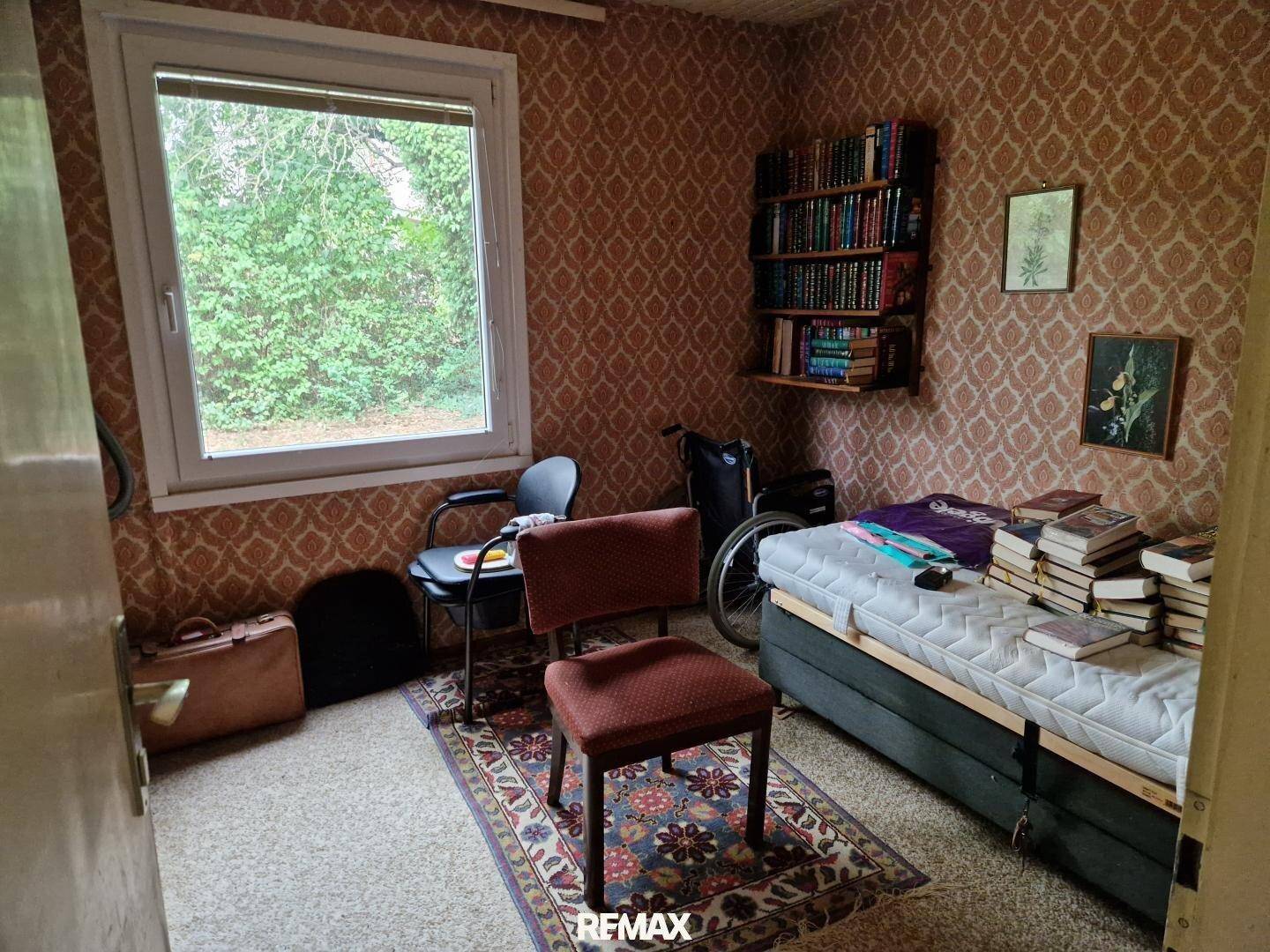 Schlafzimmer im Vintage-Stil mit gemusterter Tapete, Einzelbett und Büchern.