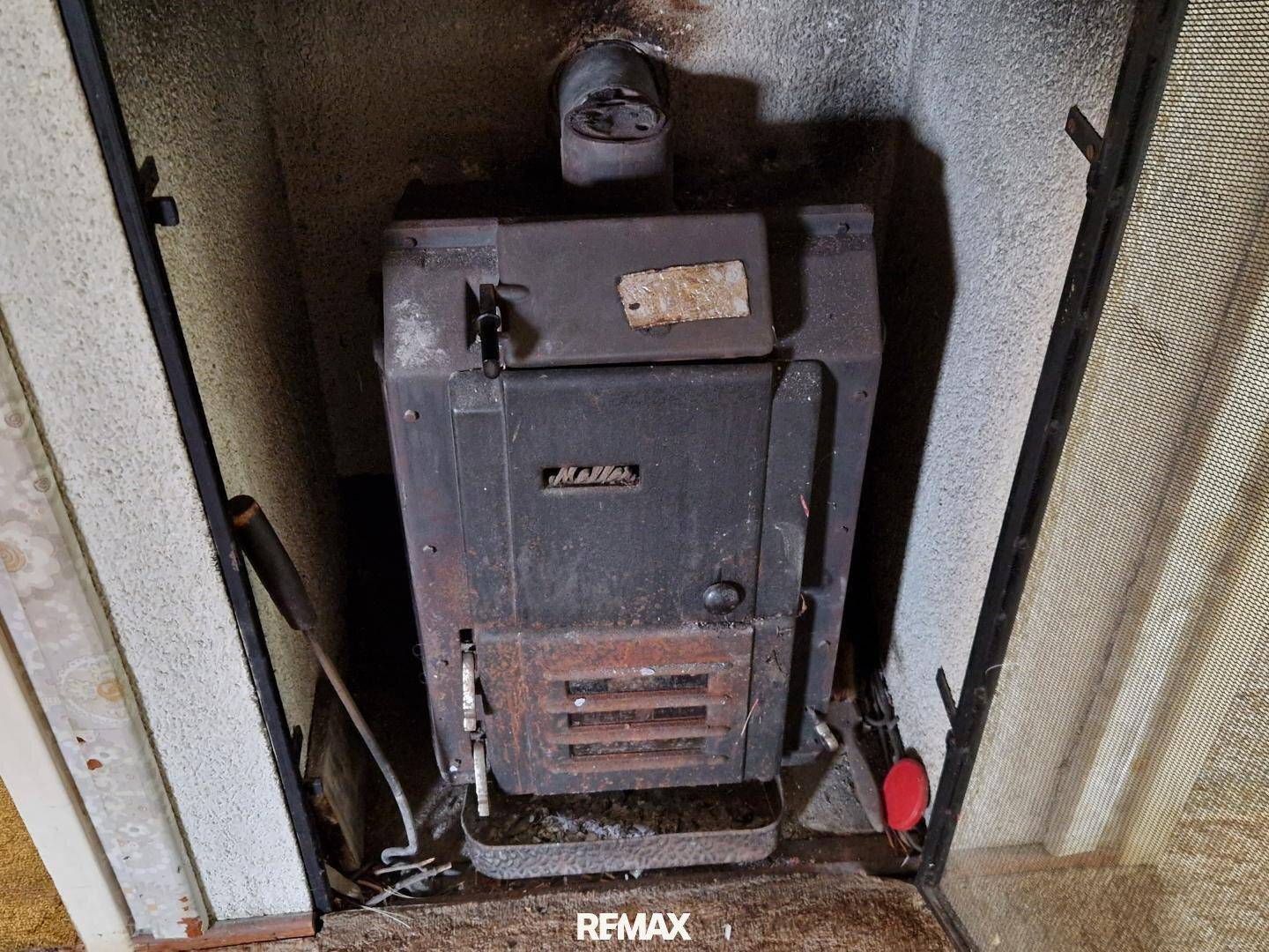 Alter Ofen in einer Nische, möglicherweise für Heizungszwecke, mit sichtbaren Gebrauchsspuren.