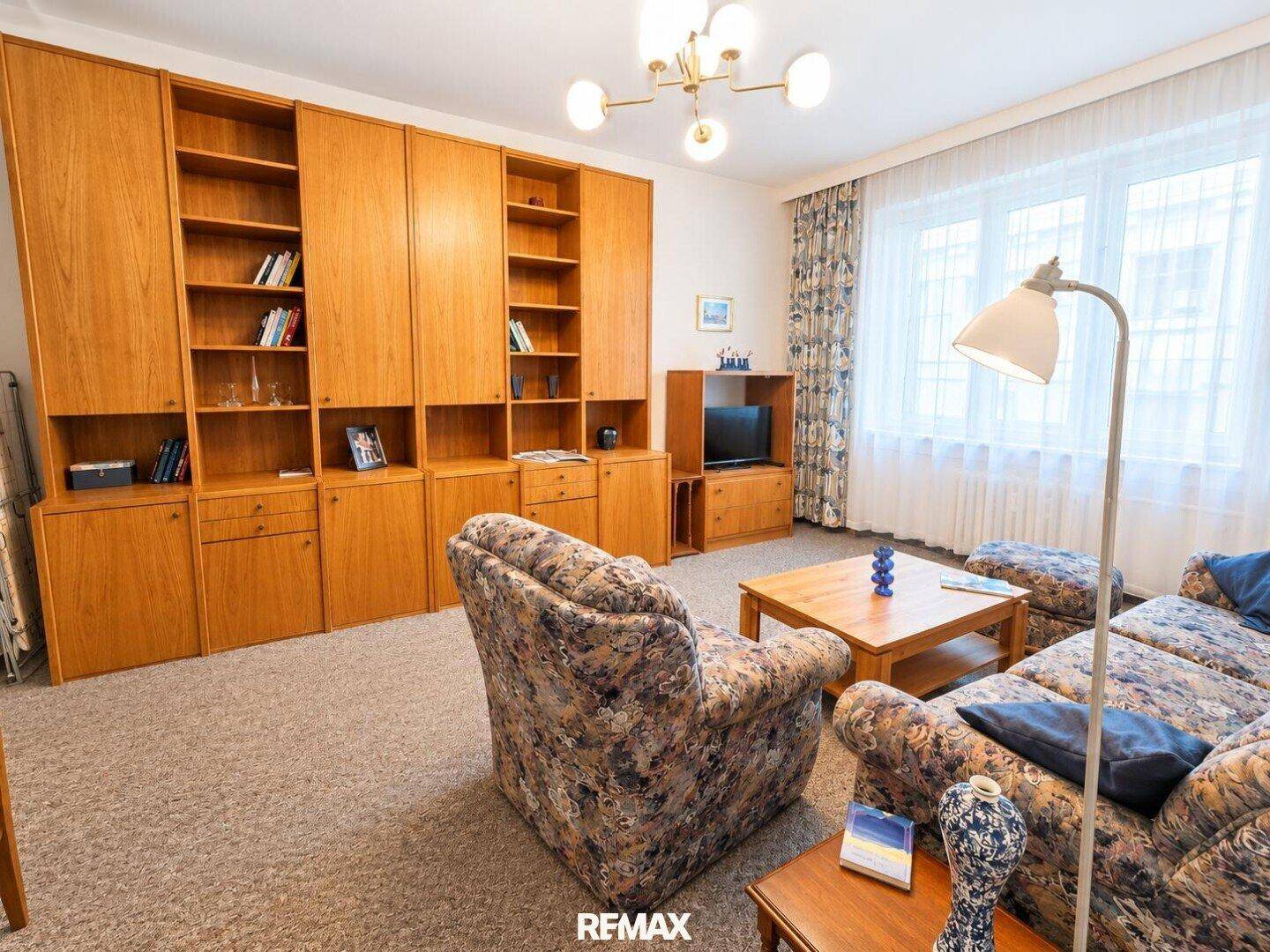 Geräumiges Wohnzimmer mit bequemen Sitzmöbeln, Holzmöbeln und großem Fenster.
