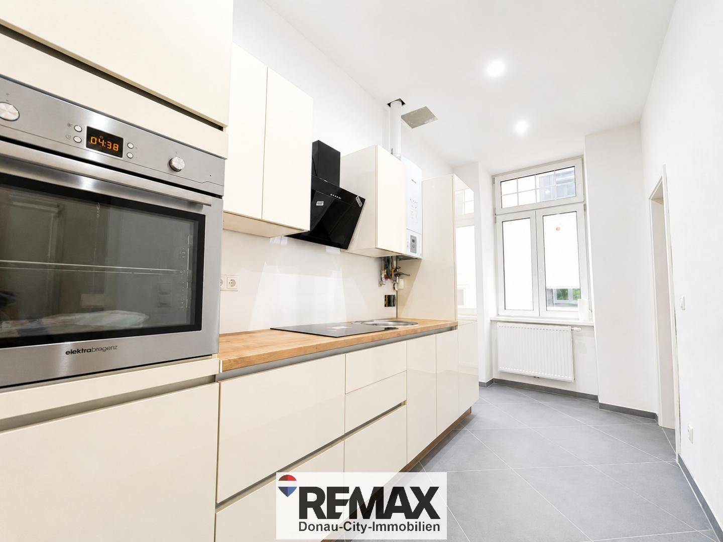 Moderne Einbauküche mit hellen Fronten, Holz-Arbeitsplatte und integriertem Backofen.