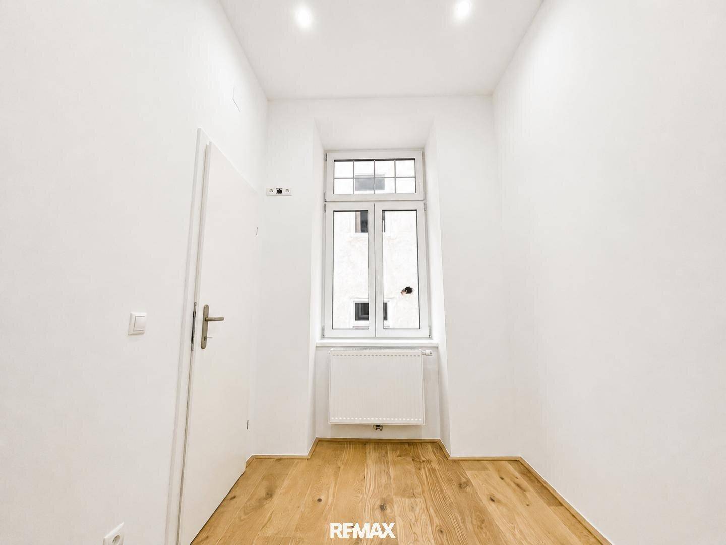 Kleiner, heller Raum mit Holzboden und einem hohen Fenster, ideal als Büro oder Kinderzimmer.