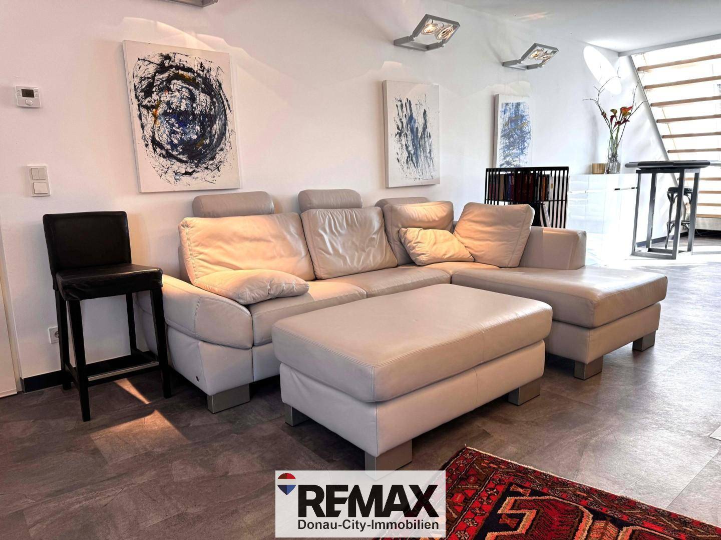 Gemütliches Wohnzimmer mit großem Ecksofa, modernen Kunstwerken und Teppichboden.