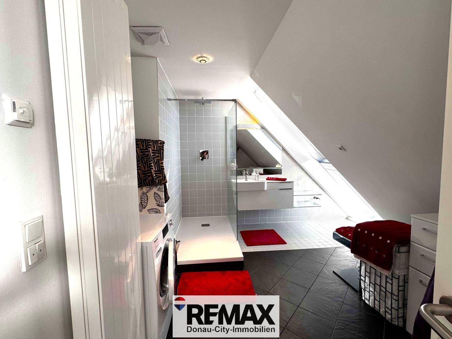 Modernes Badezimmer mit begehbarer Dusche, Waschmaschine und Dachfenster.