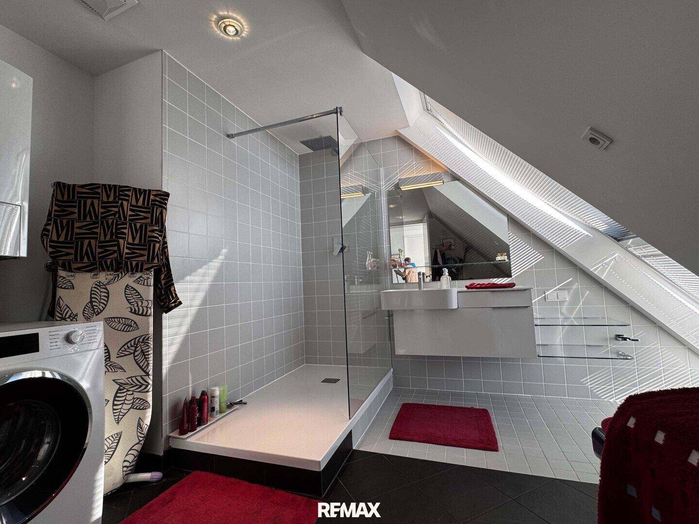 Helles Badezimmer mit großer begehbarer Dusche, modernem Waschtisch und Dachfenster.