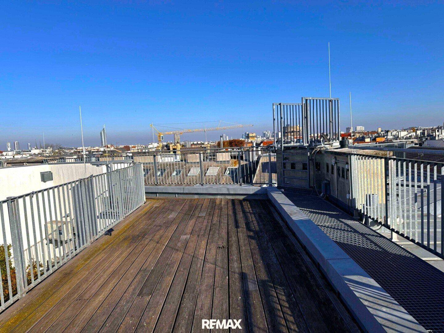 Weitläufige Dachterrasse mit Holzboden und Panoramablick auf die städtische Umgebung.