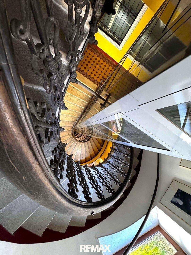 Historisches Treppenhaus mit Wendeltreppe und einem modernen Aufzug in der Mitte des Schachts.