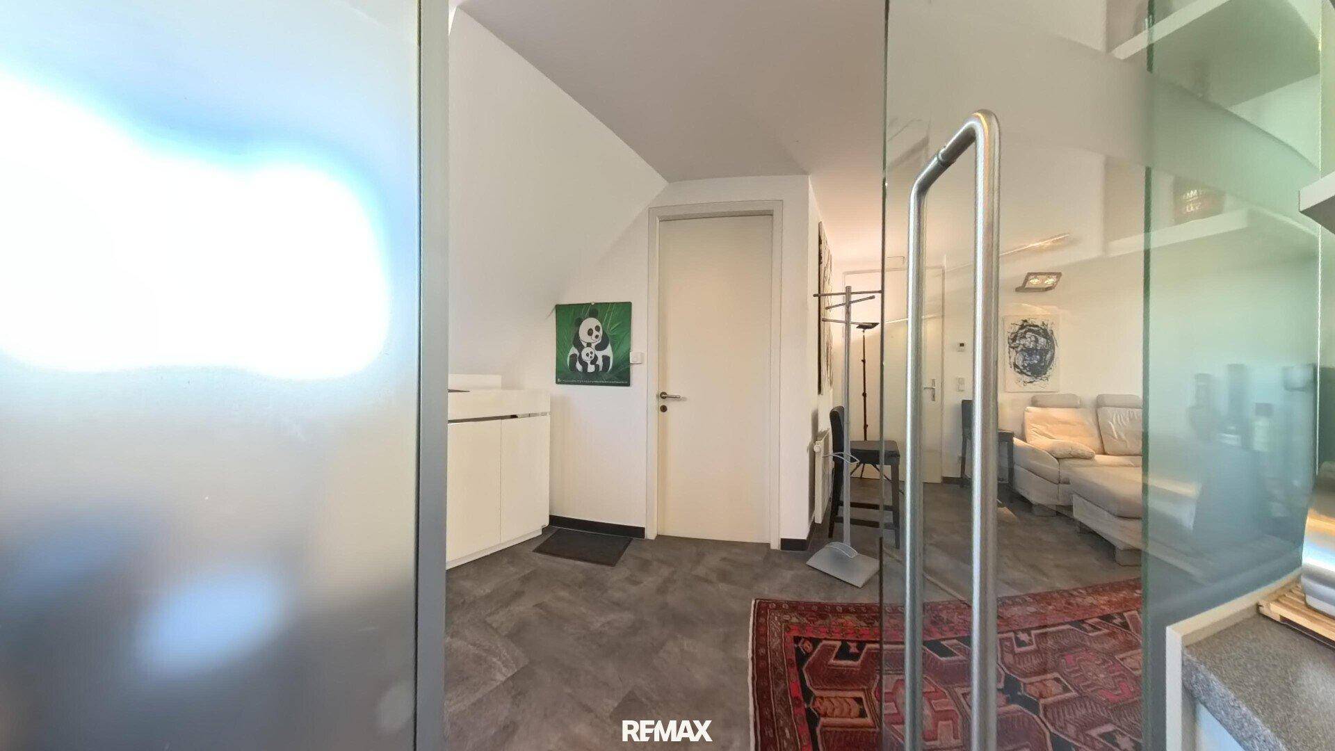 Heller Flur mit weißem Schrank, einer Tür und einem Spiegel, der den Wohnbereich reflektiert.