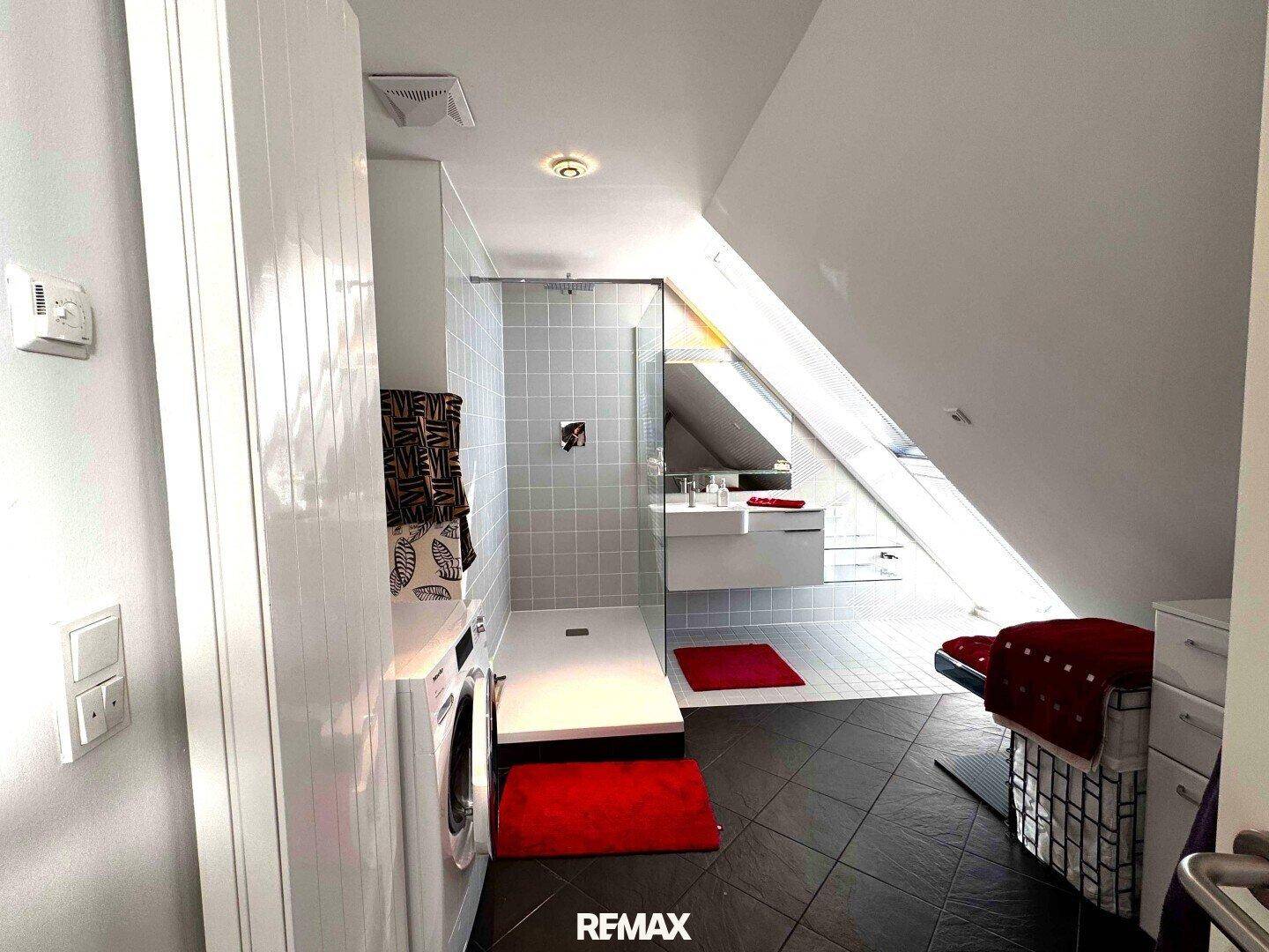 Modernes Badezimmer mit begehbarer Dusche, Waschmaschine und Dachschräge mit Oberlicht.