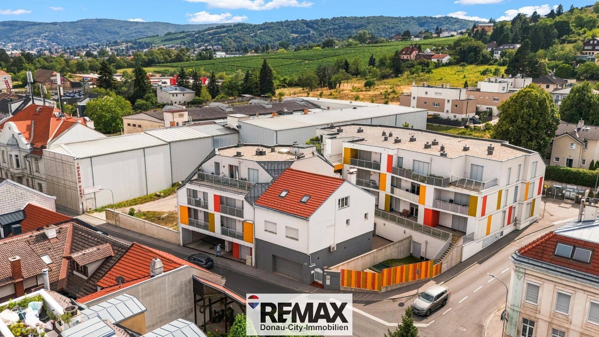 Weitläufige Luftaufnahme des Wohnkomplexes mit umliegender Landschaft und Bergen im Hintergrund.