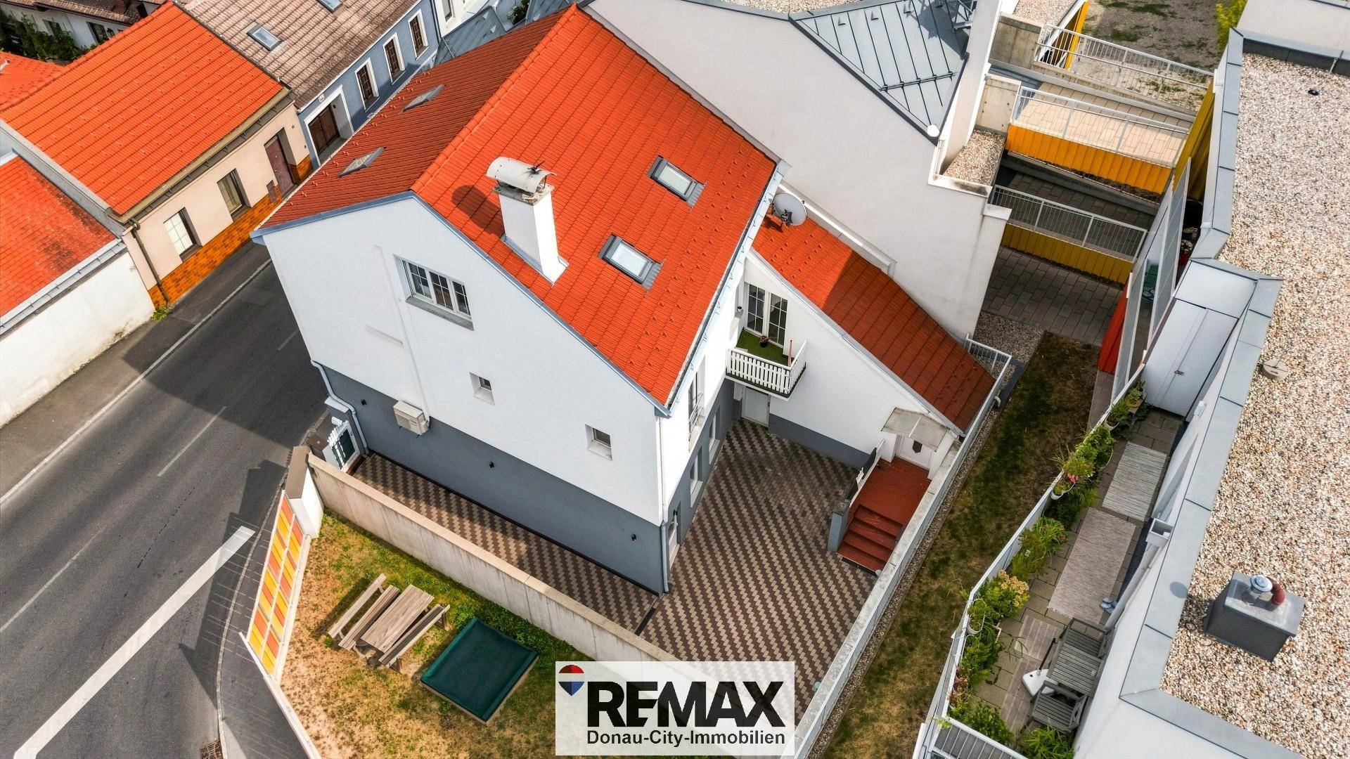 Luftaufnahme des Hauses mit rotem Dach, gepflastertem Innenhof und kleinem Balkon.