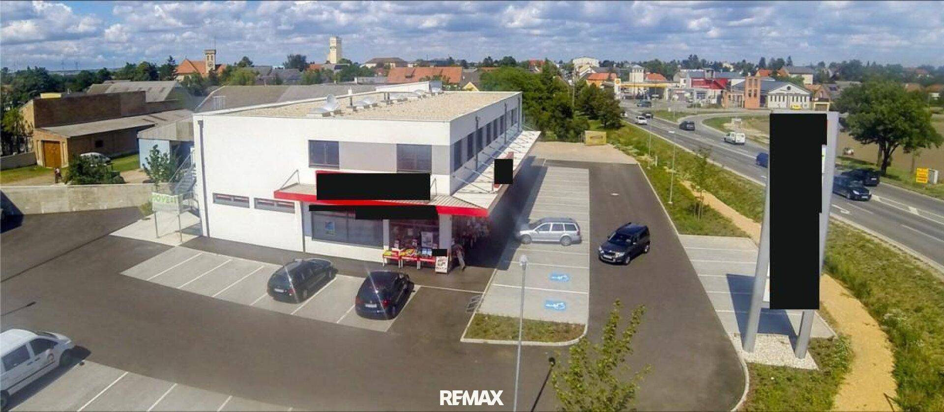 Eine weitere Luftansicht des Geschäftsgebäudes mit Parkplätzen, umgeben von einer ländlichen und städtischen Umgebung.