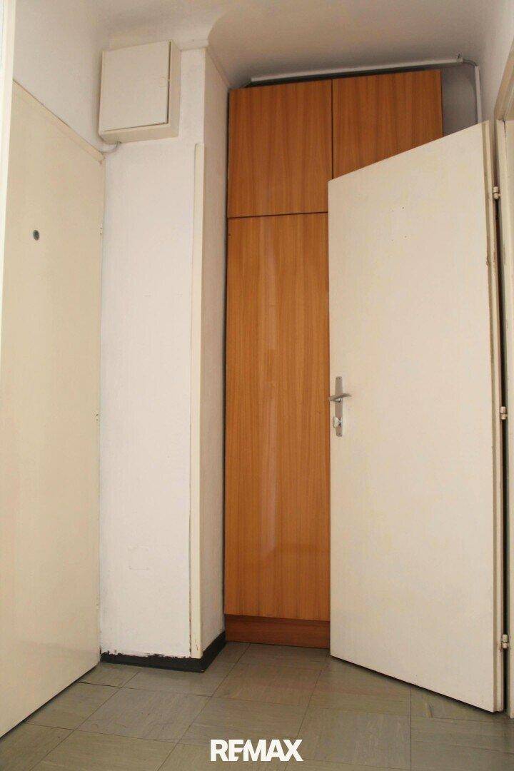Flur mit Fliesenboden und einem praktischen Einbauschrank aus Holz für zusätzlichen Stauraum.