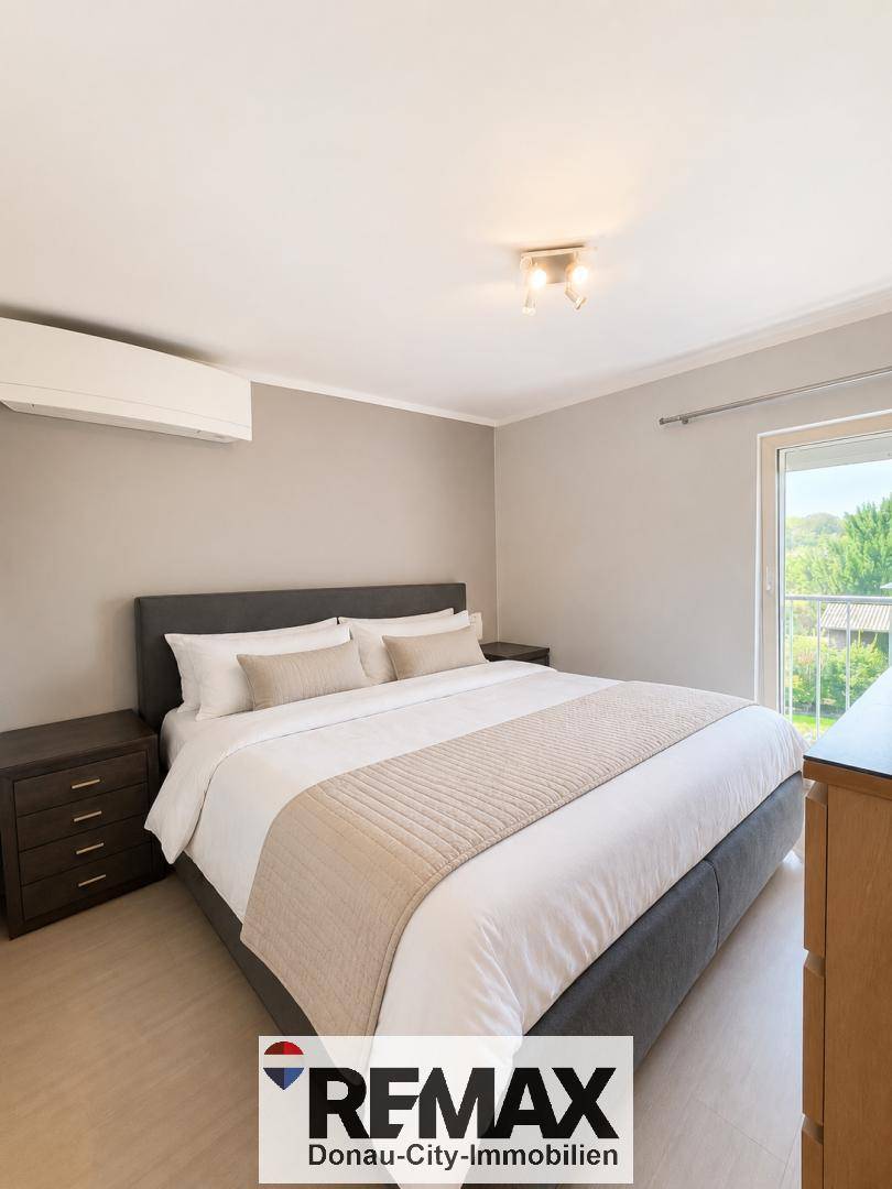 Gemütliches Schlafzimmer mit großem Doppelbett, Klimaanlage und Zugang zu einem Balkon.